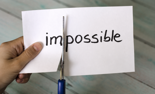 Une main découpe le mot « impossible » sur une feuille blanche pour faire apparaître le mot « possible ».
